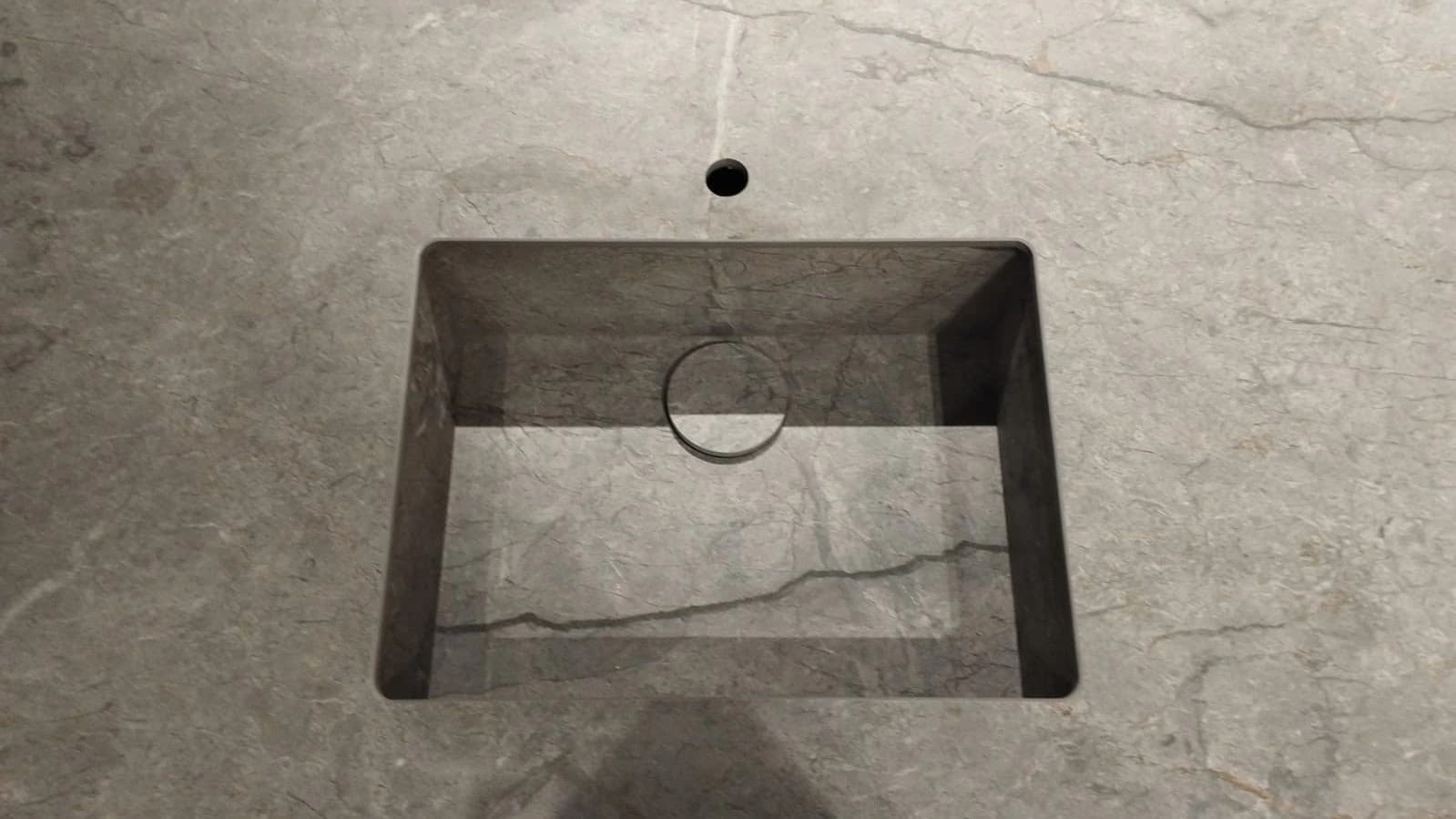 Detalle de una cubeta gris y de su desagüe.