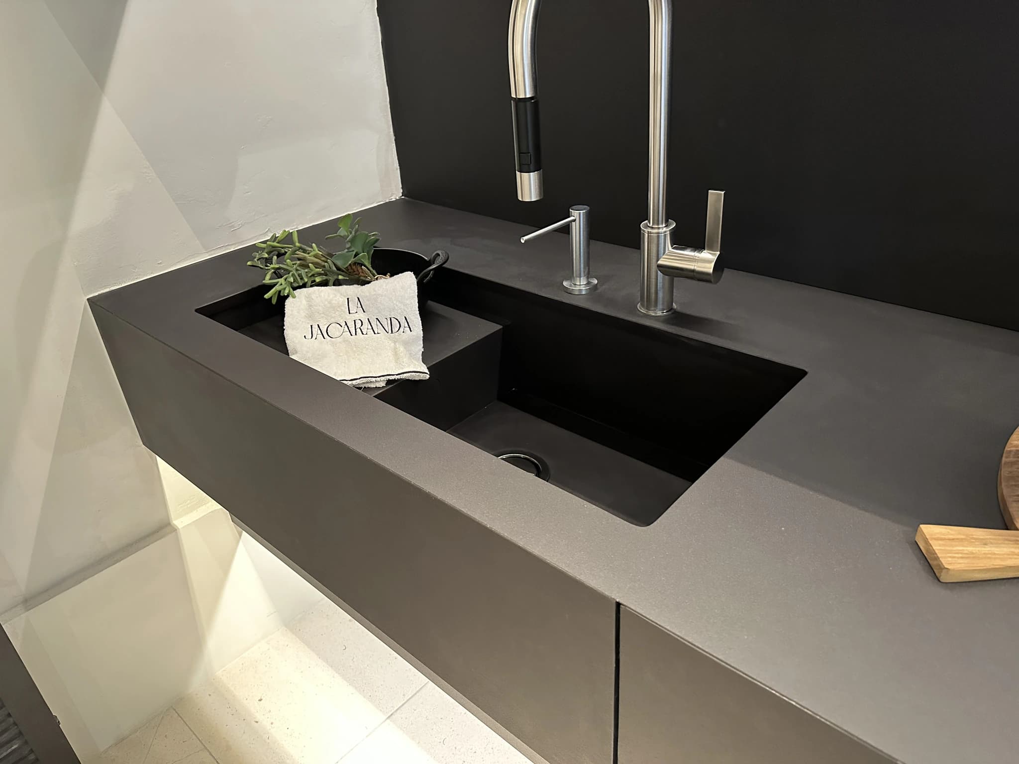 Detalle de un lavabo rectangular oscuro con grifo instalado.