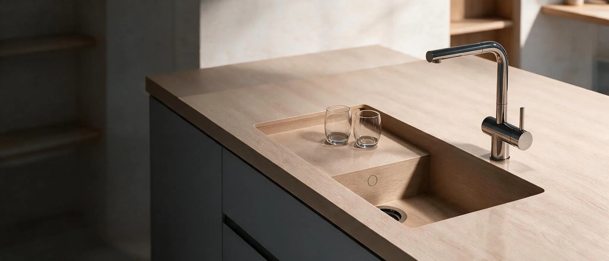 Light-toned kitchen countertop with integrated sink, tap and two glasses