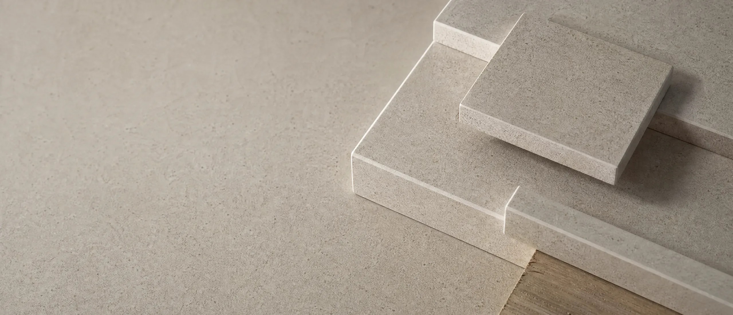 Light-colored speckled surface with several rectangular samples of the same material and a wood detail at the bottom